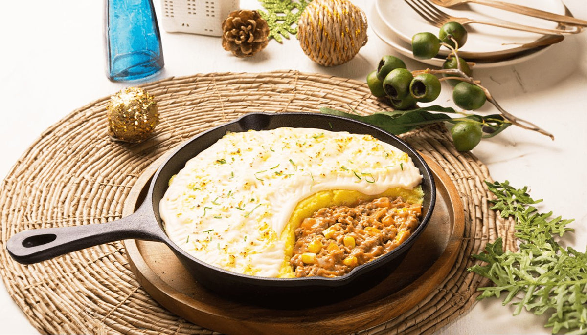 Creamy shepherd's pie in a cast iron skillet with a scoop taken out to show the meat and corn layer