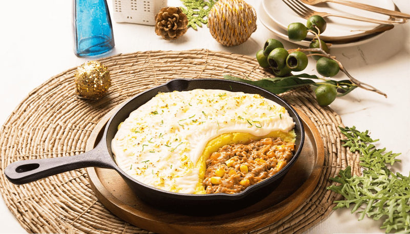 Creamy shepherd's pie in a cast iron skillet with a scoop taken out to show the meat and corn layer
