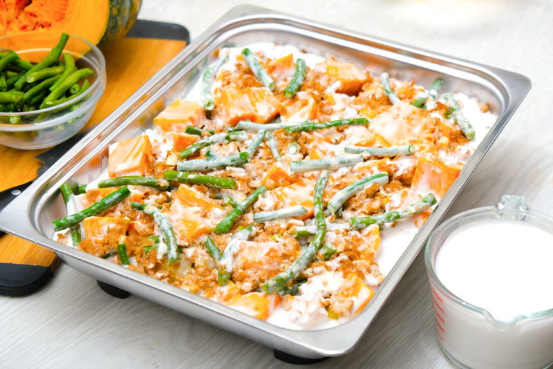 Ginataang gulay in coconut milk plated in a food service tray with kalabasa and sitaw