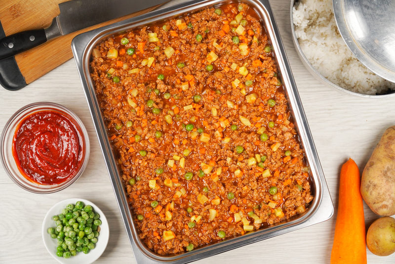 Argentina red giniling in a food service tray with peas and carrots, served with ketchup on the side