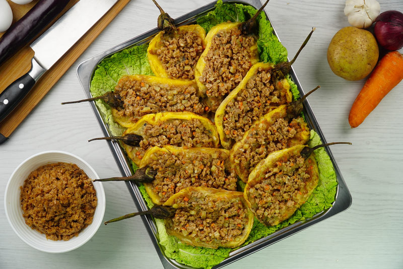 Tortang talong stuffed with seasoned giniling, plated on lettuce in a food service tray