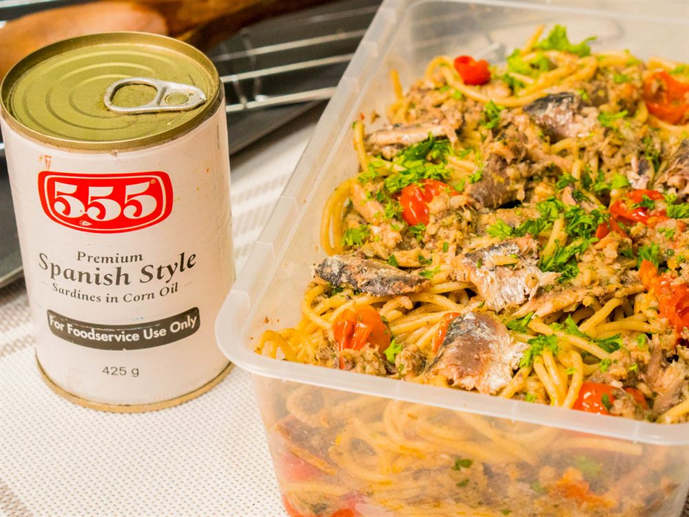 Sardine aglio olio batched in a food service tub beside a 555 Premium Spanish Style Sardines food service can