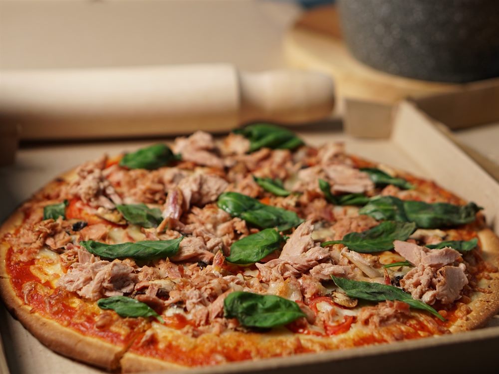 Tuna and basil pizza resting in a delivery box on a pizza line, a menu application for CPFS Tuna Flakes in Brine