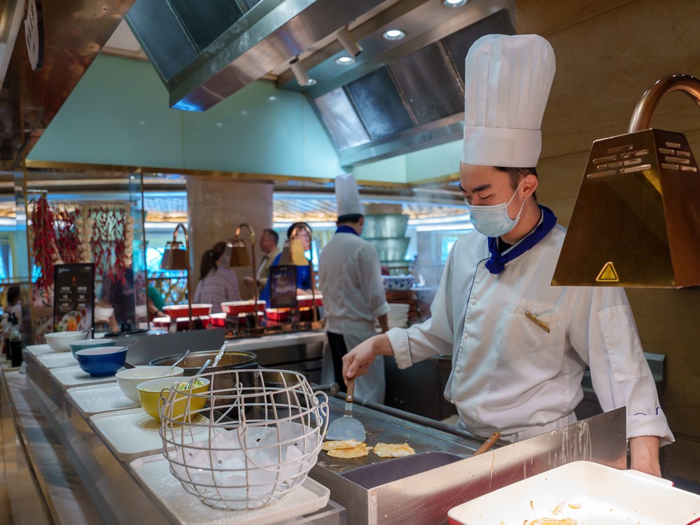 A chef preparing an omelette to order at a hotel buffet cooking station
