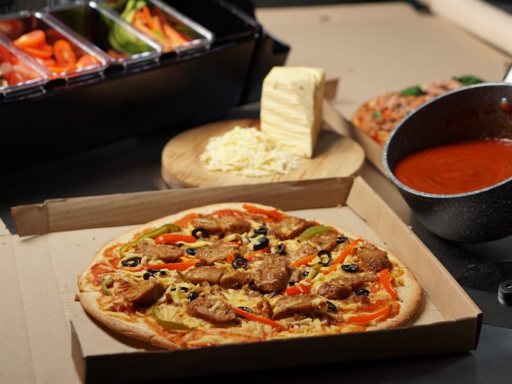 Plant-based sausage and pepper pizza in a delivery box, a menu application for unMeat Hungarian Sausage